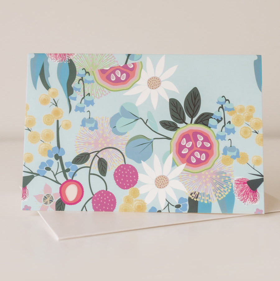 A greeting card with a blue background and a floral design featuring various flowers and fruit illustrations.